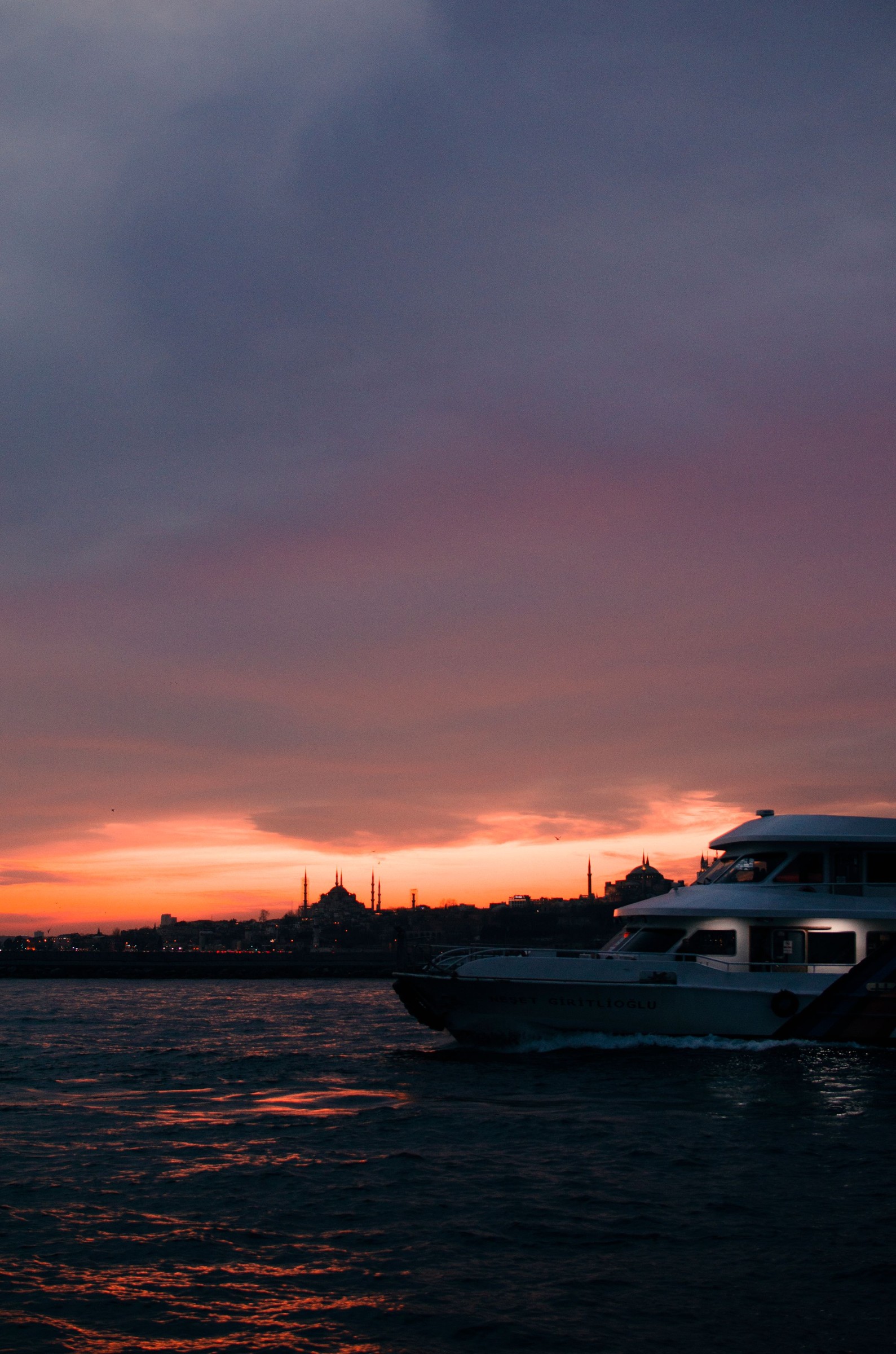 Yacht silhouetted on the sea beneath a colorful sunset sky.