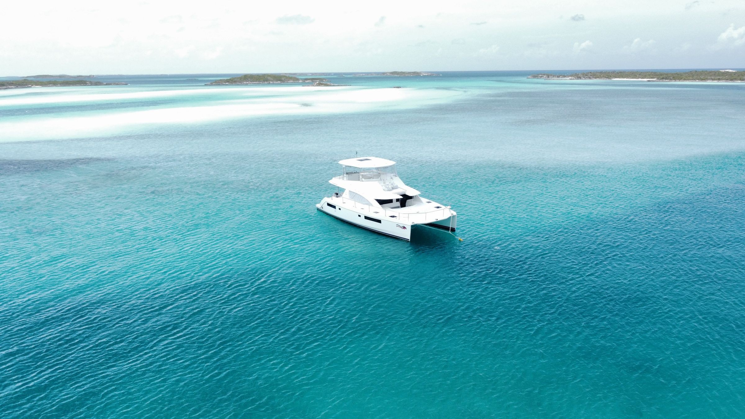 Aerial view of a white yacht surrounded by turquoise water.