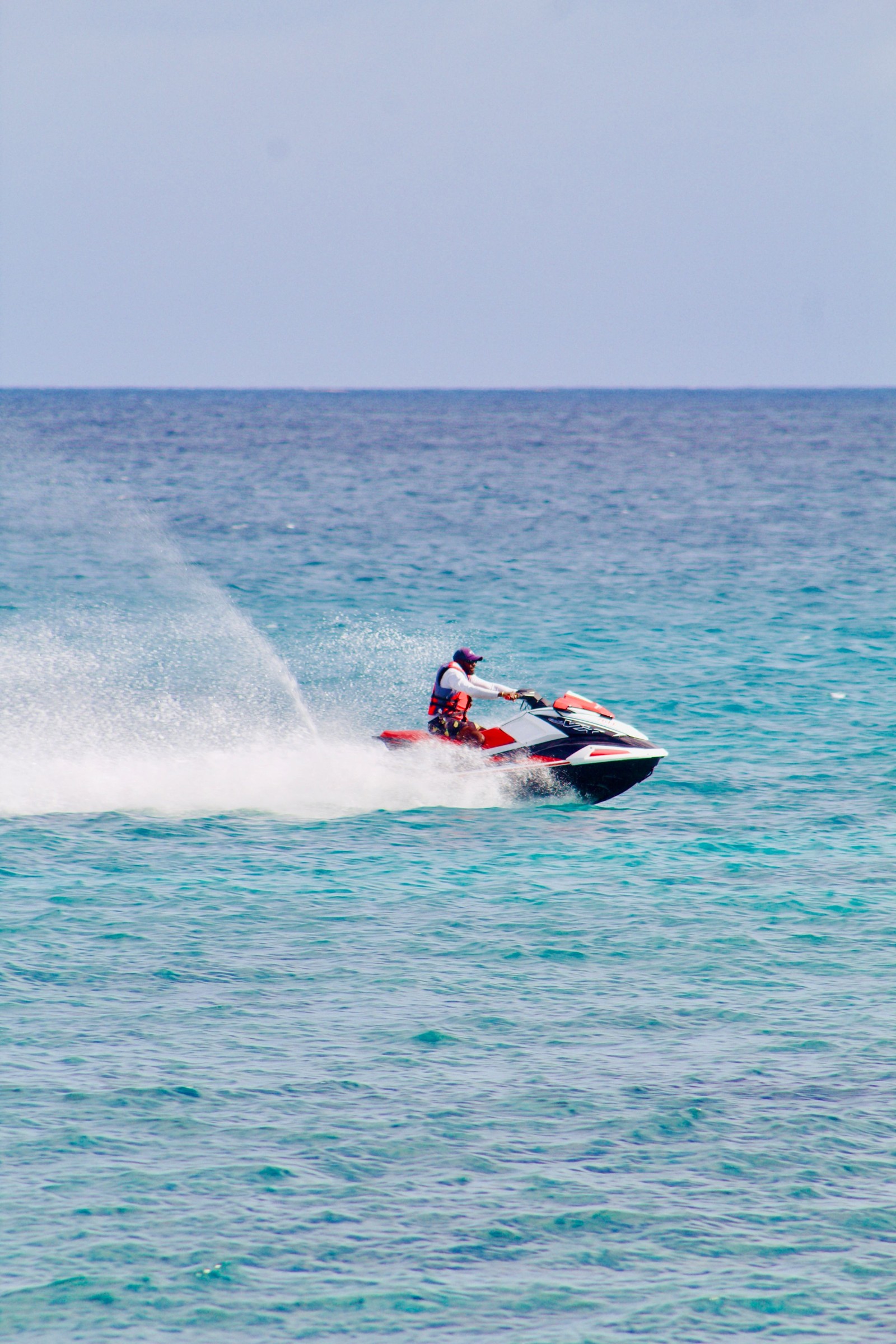 Jet ski rider traveling across bright blue water.