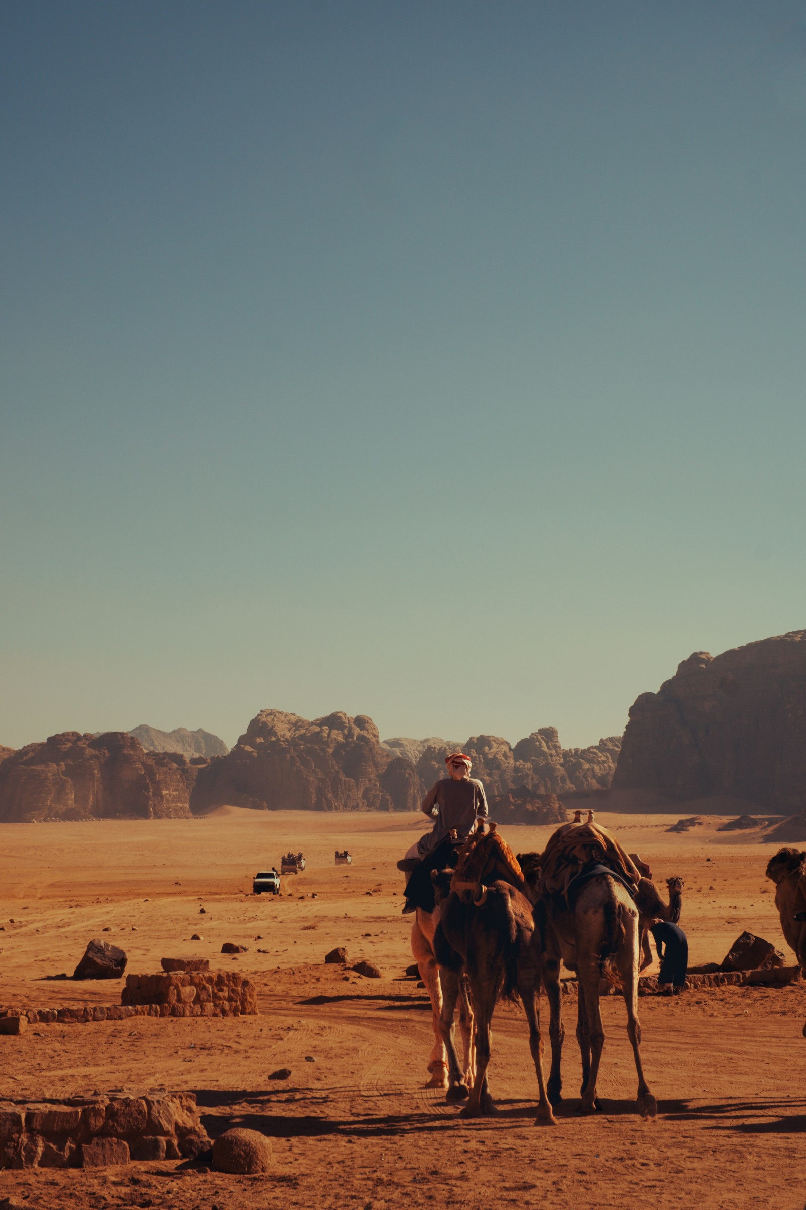 Camel rider crossing the sandy landscape of Wadi Rum.