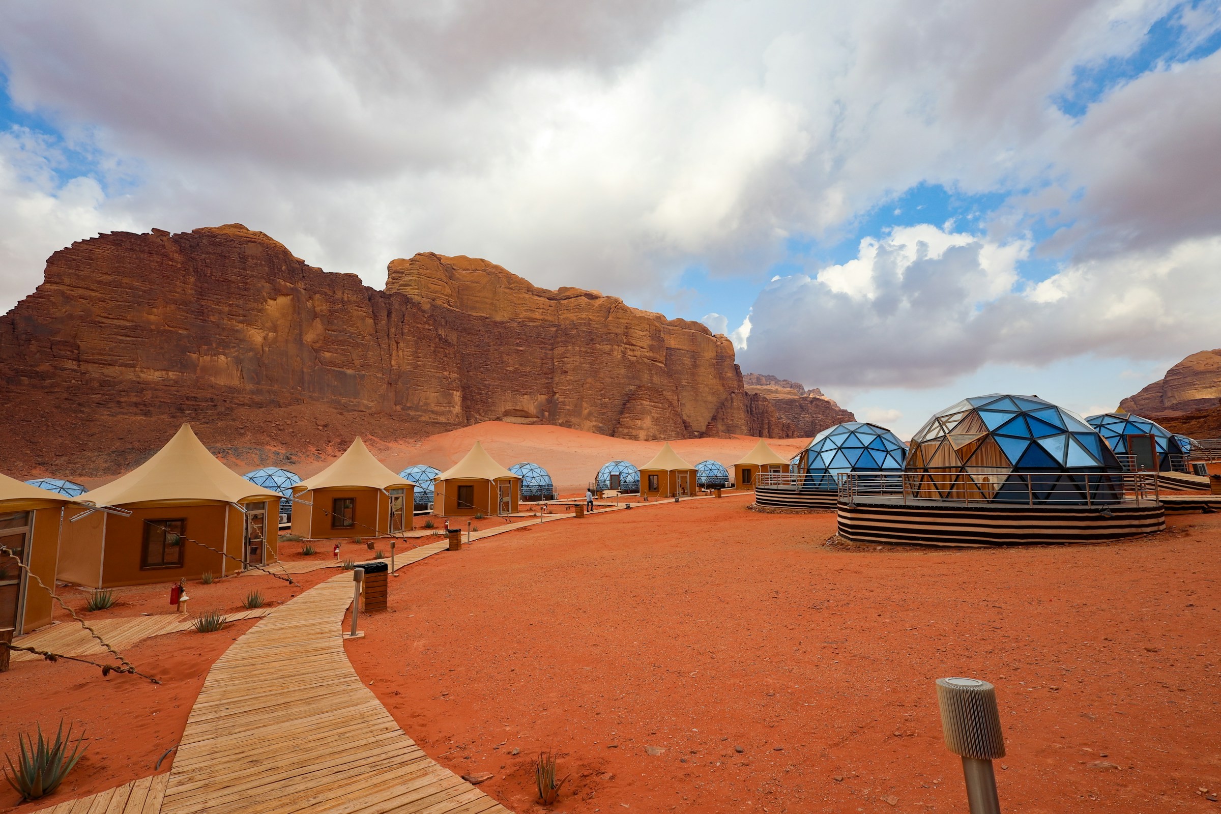 Desert camp tents beneath rocky mountains in Wadi Rum.