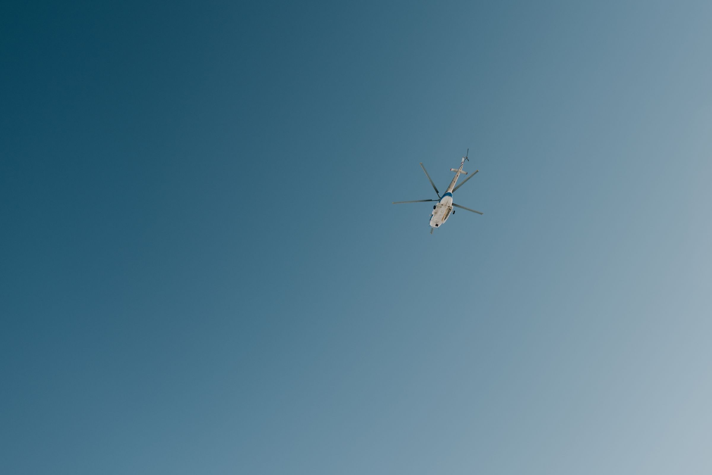 Helicopter flying across a clear blue sky.