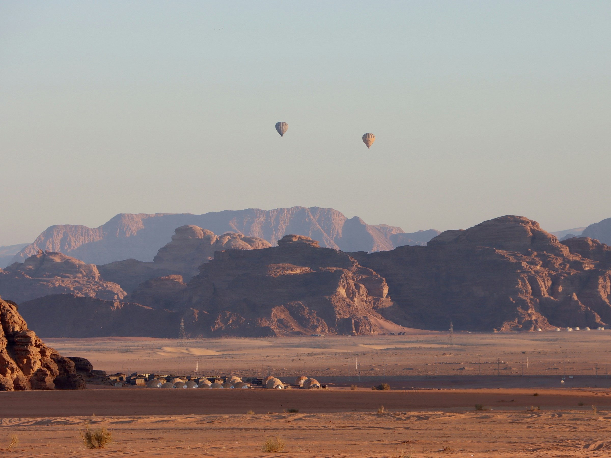 Two hot air balloons floating above the Wadi Rum desert.