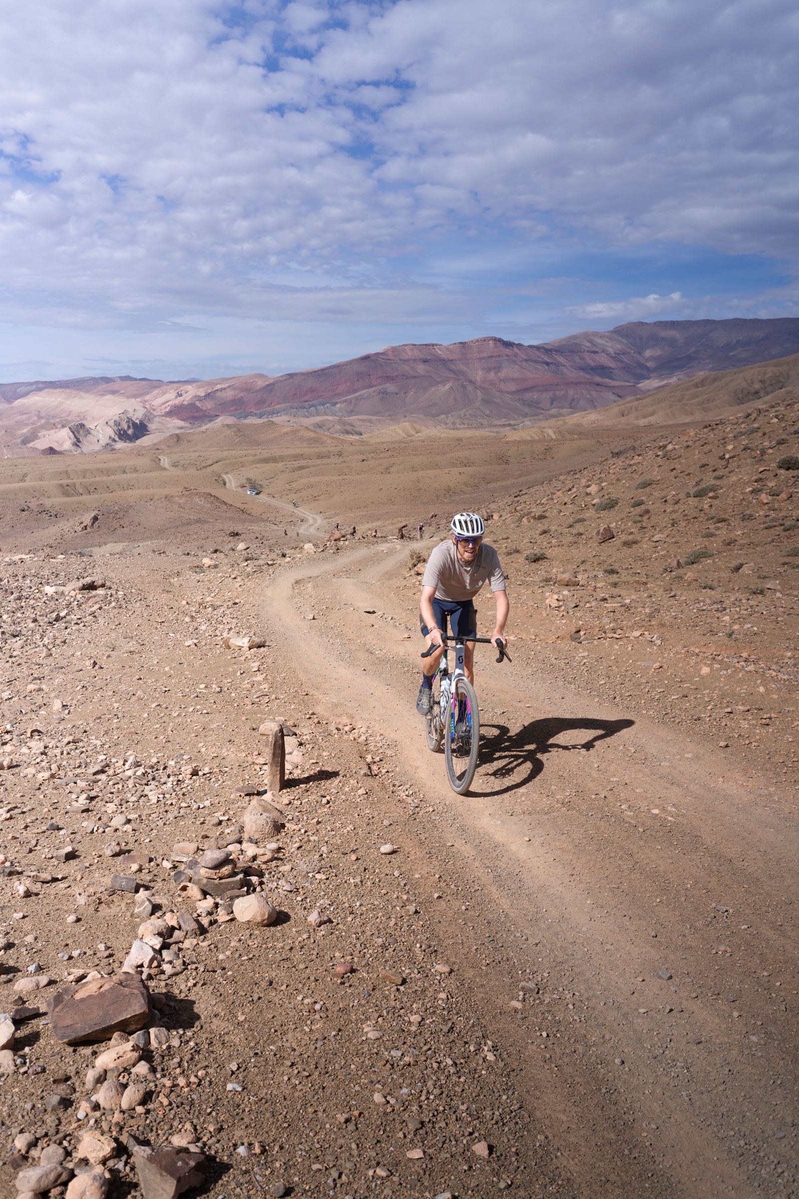 Cyclist riding along a rocky desert track with distant mountains.