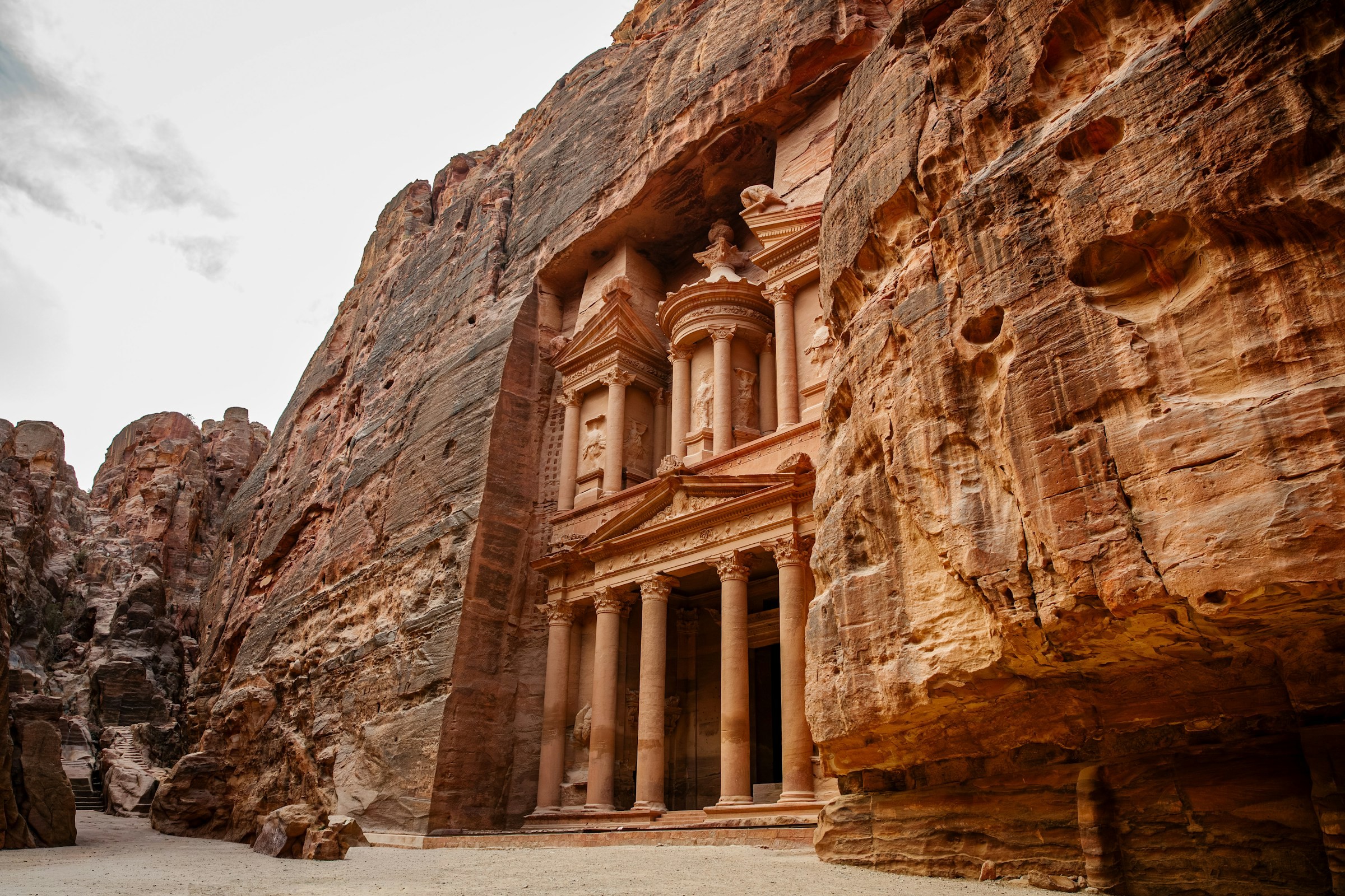 The ornate Treasury building carved into red sandstone cliffs at Petra.