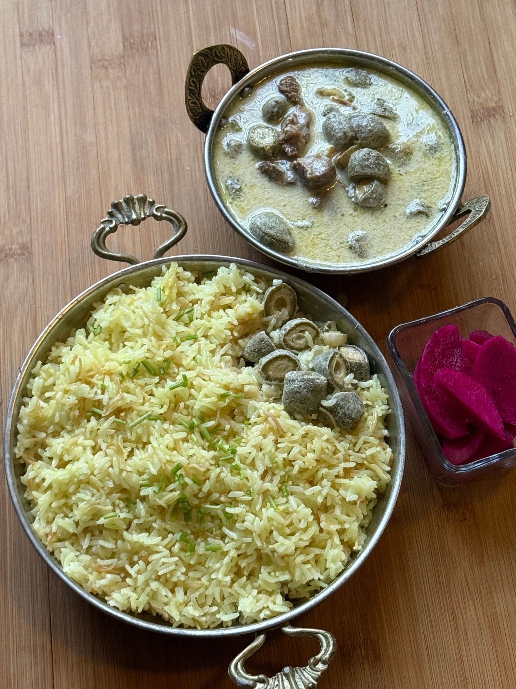 Traditional mansaf with rice, sauce and pickled radishes on a wooden table.