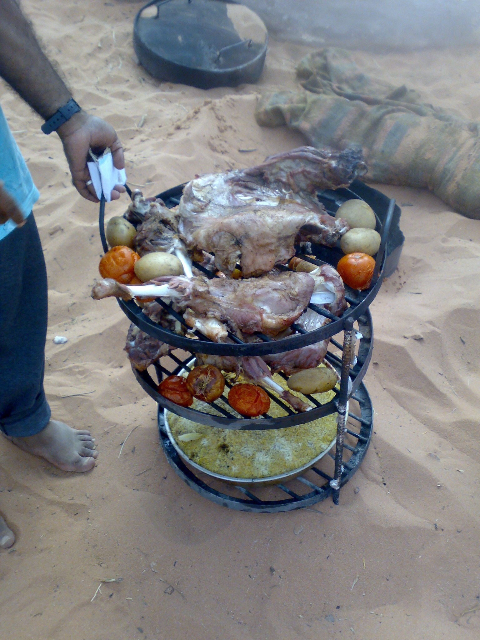 Cooked zarb on stacked metal trays in Wadi Rum.