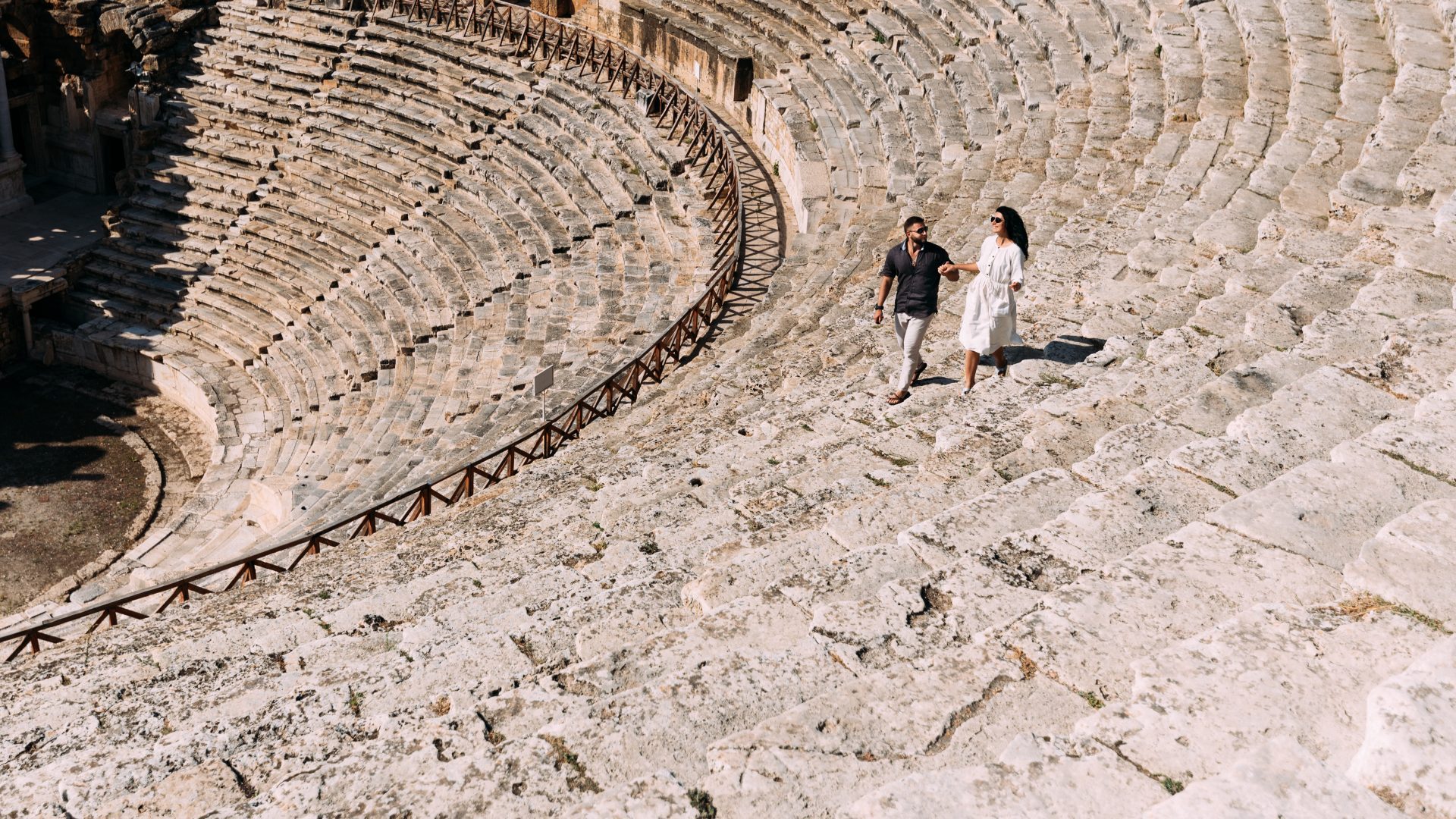 Couple walking through the ancient Roman amphitheater in Amman, Jordan, surrounded by historic stone seating and archaeological architecture