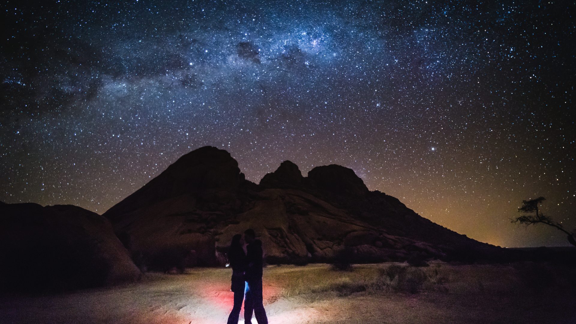 Stargazing in Wadi Rum, Jordan, under a spectacular Milky Way night sky, with dramatic desert mountains and travelers enjoying the star-filled landscape