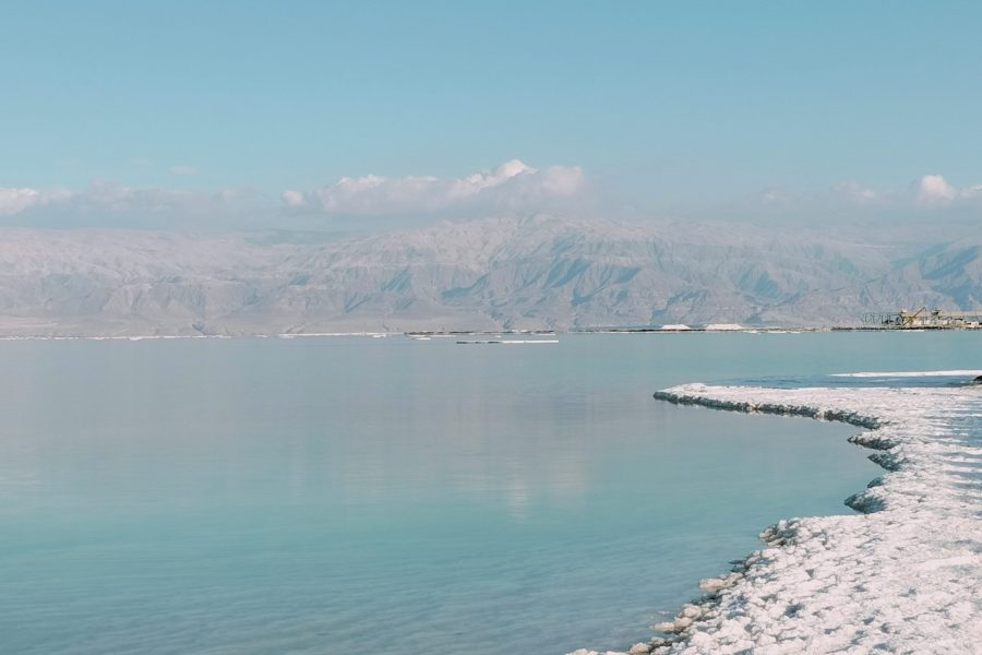 Salt-covered shoreline of the Dead Sea with mountains in Jordan