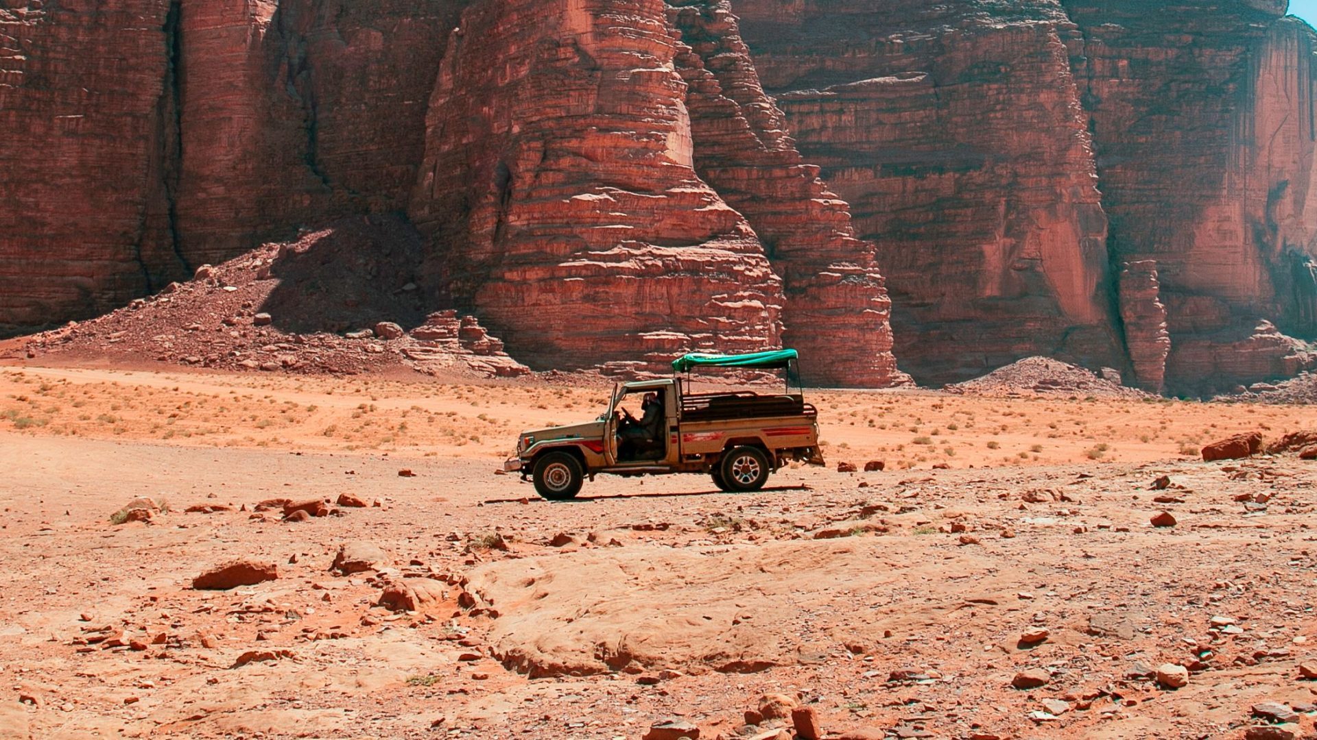 4x4 Jeep safari tour in Wadi Rum desert, Jordan, surrounded by massive red sandstone cliffs