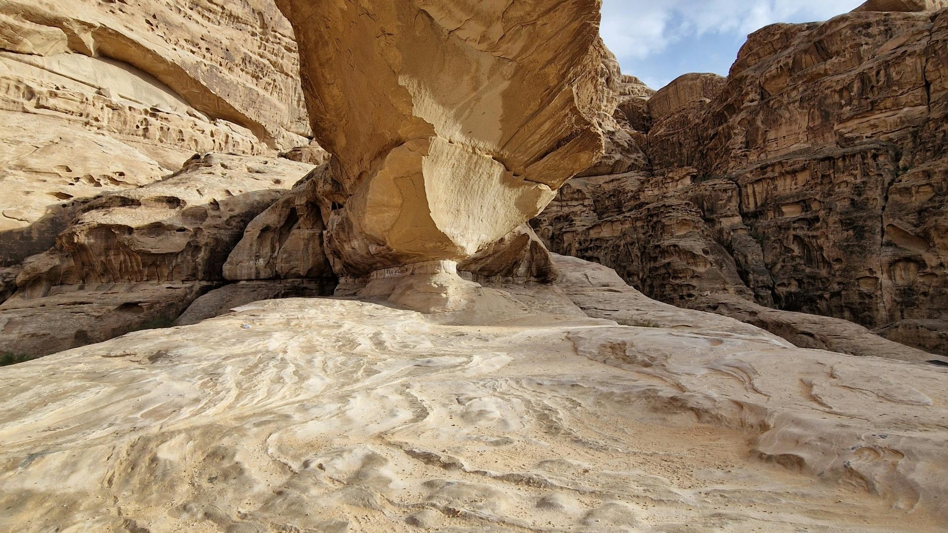 Natural sandstone rock formations in Wadi Rum, Jordan, featuring a dramatic desert rock arch and weathered stone landscape