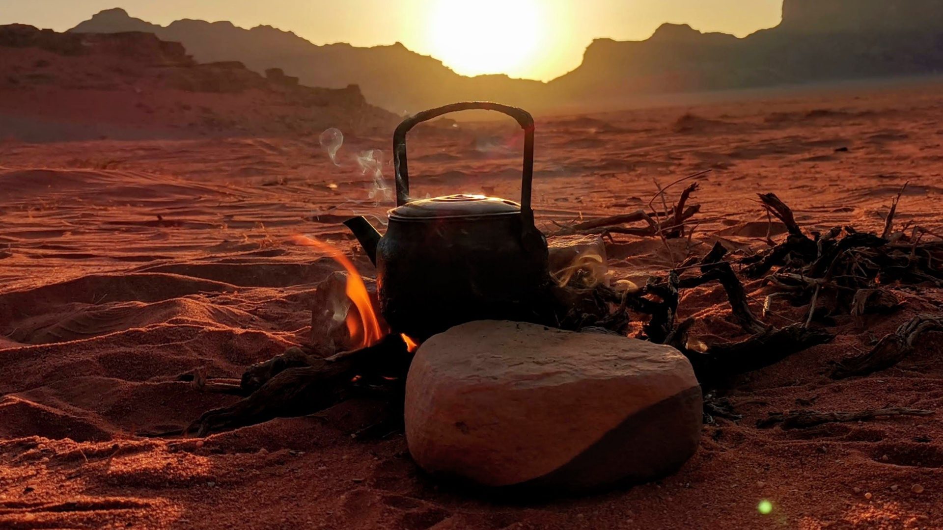 Traditional Bedouin tea brewing over a campfire at sunset in Wadi Rum desert, Jordan