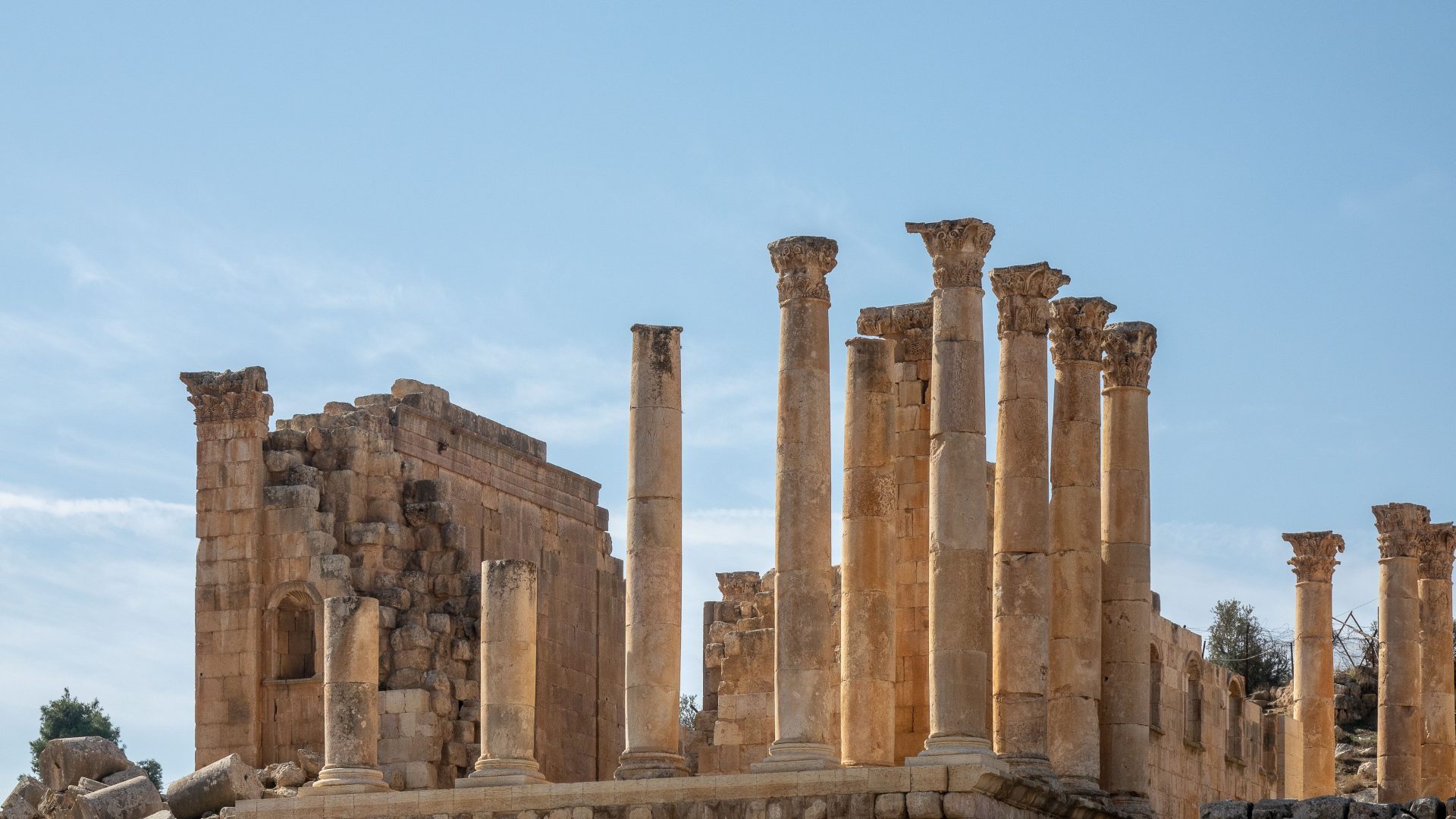 Ancient Roman ruins of Jerash, Jordan, featuring tall historic stone columns and archaeological remains under a clear blue sky