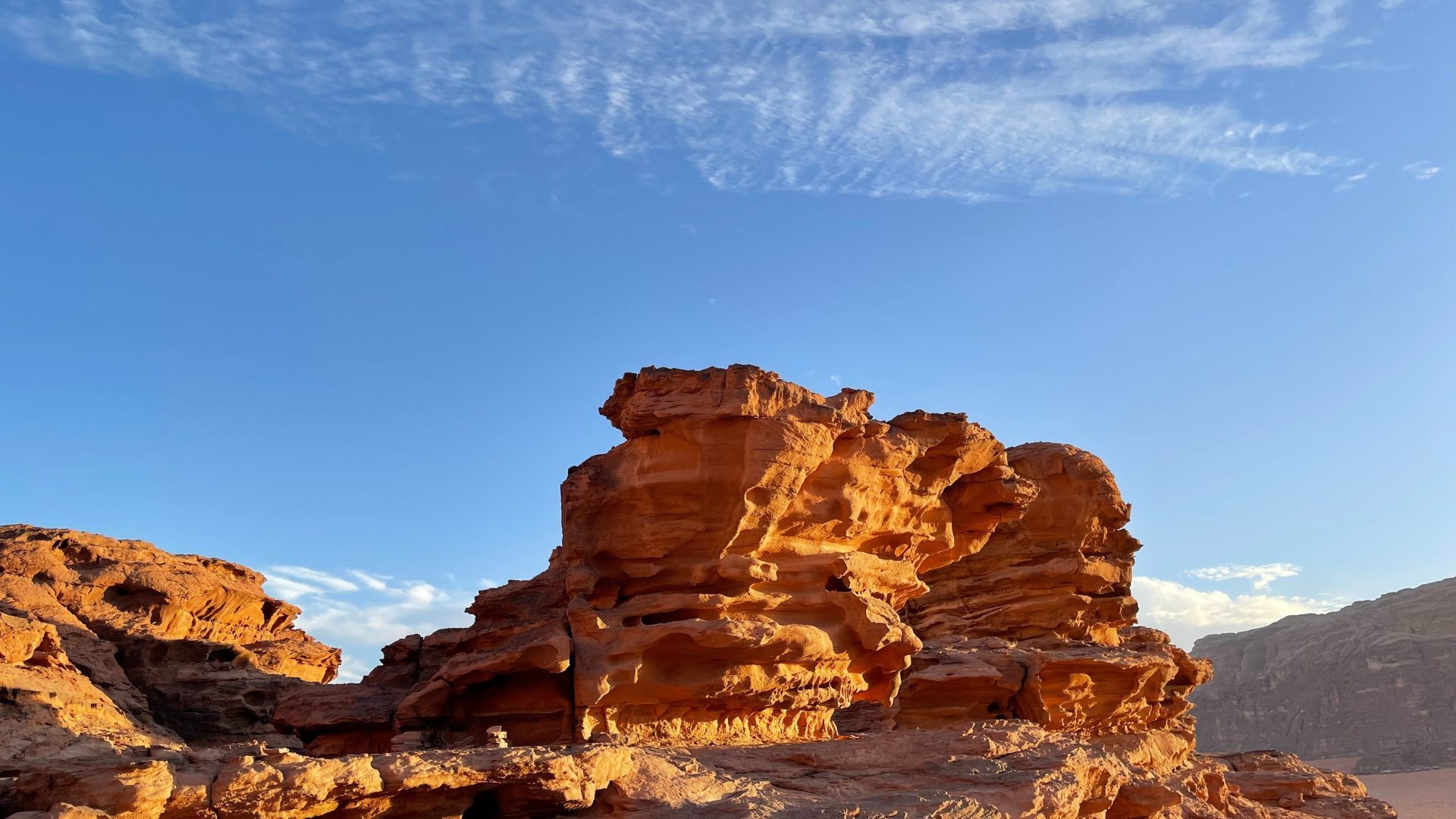 Dramatic sandstone rock formations in Wadi Rum desert, Jordan, illuminated by warm golden sunlight under a blue sky
