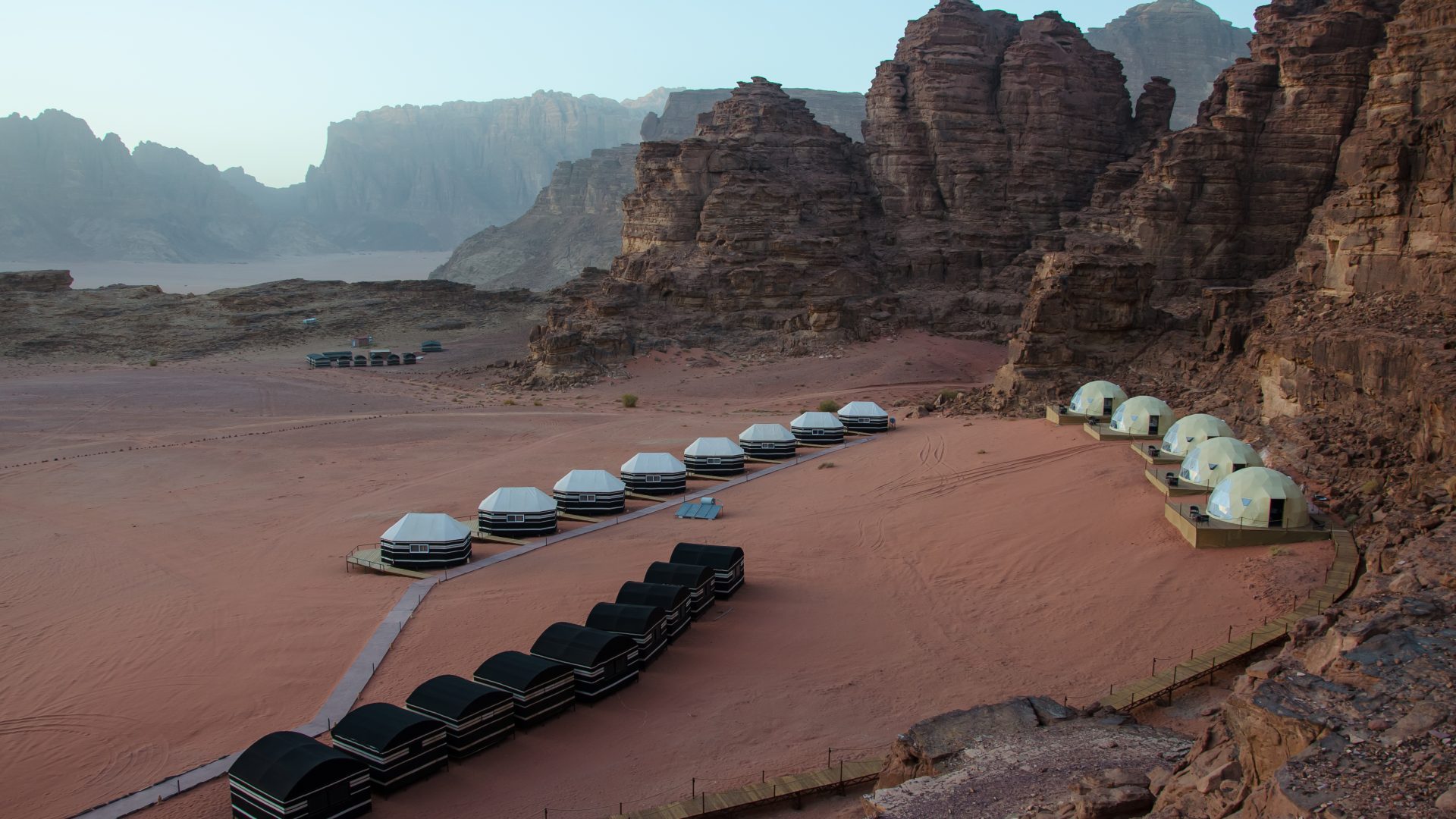 Wadi Rum luxury desert camp in Jordan surrounded by dramatic sandstone mountains, featuring panoramic bubble tents and Bedouin-style accommodation