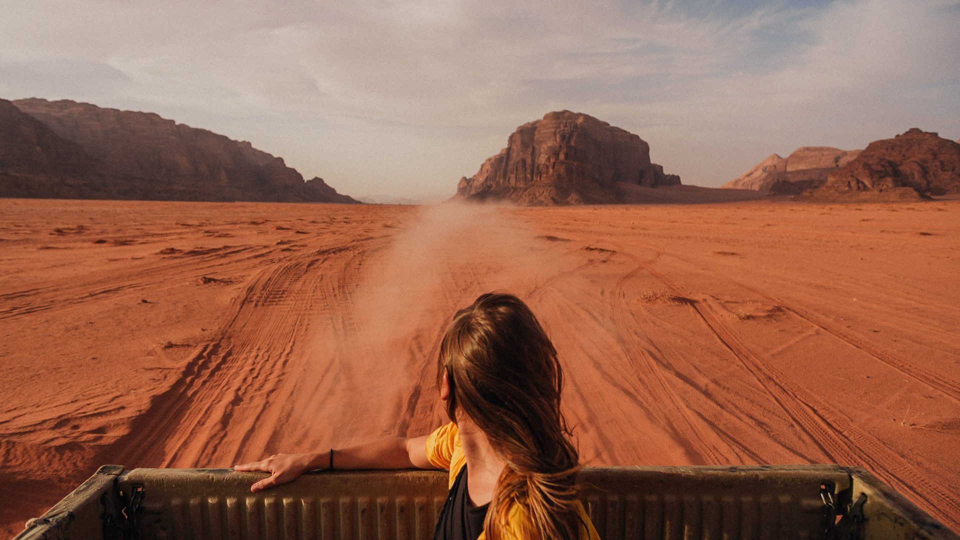 Tourist enjoying an open-top 4x4 Jeep safari through the Wadi Rum desert in Jordan, surrounded by dramatic sandstone mountains